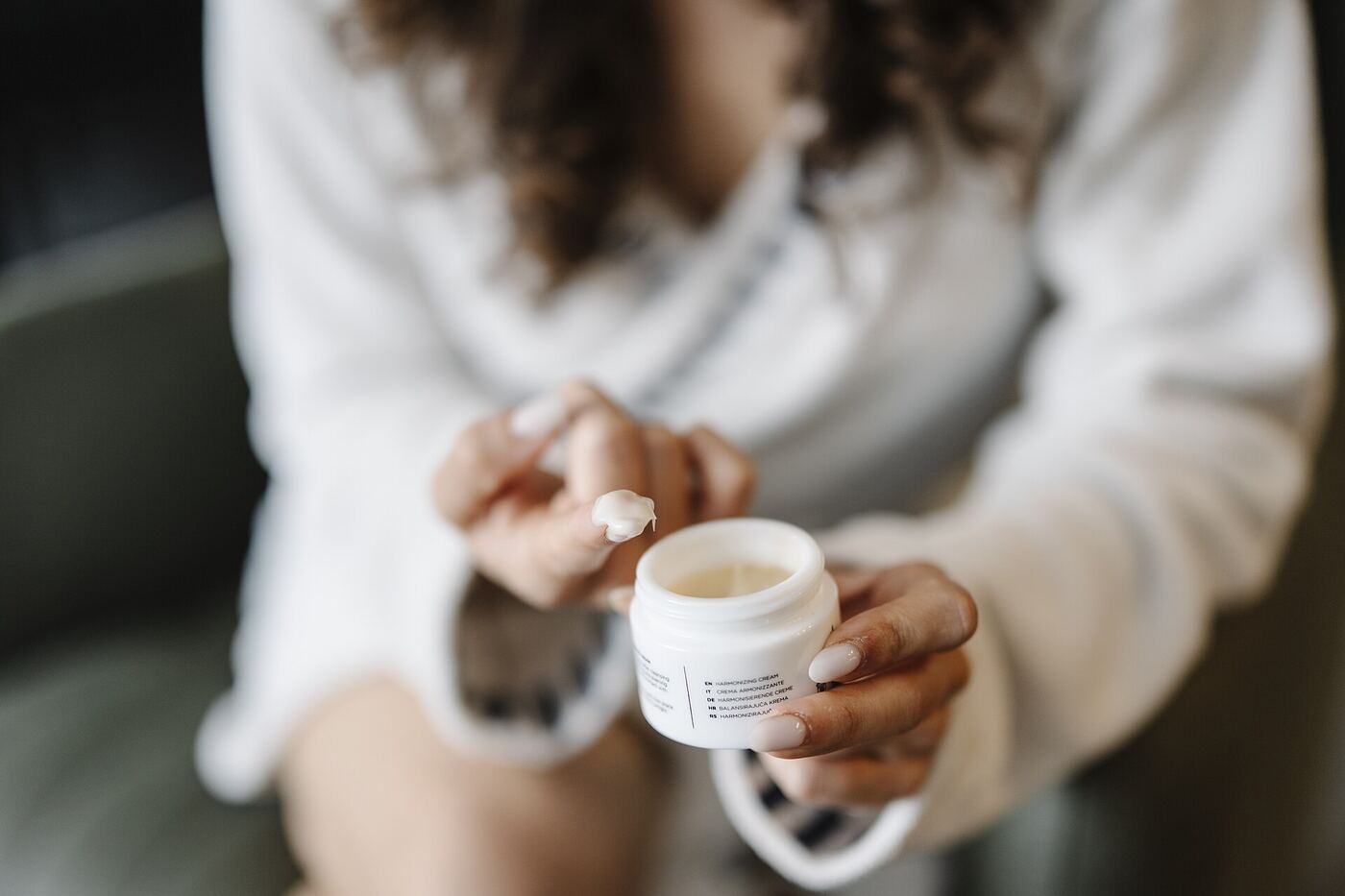 Person applying cream from a small jar