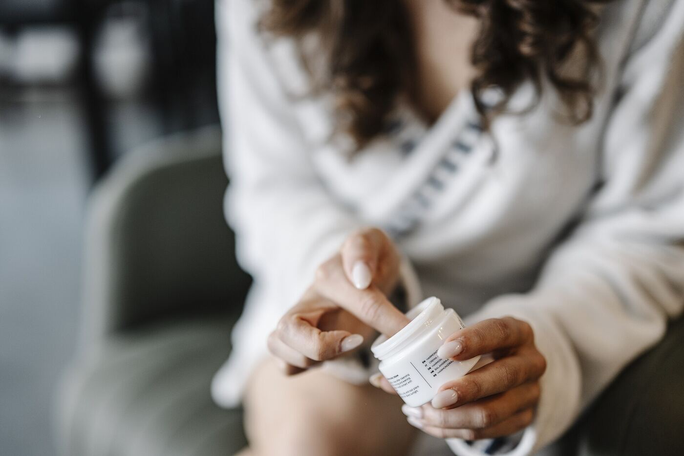 Woman applying face cream from a jar